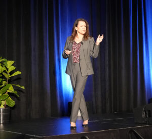 Woman speaker on stage with black backdrop